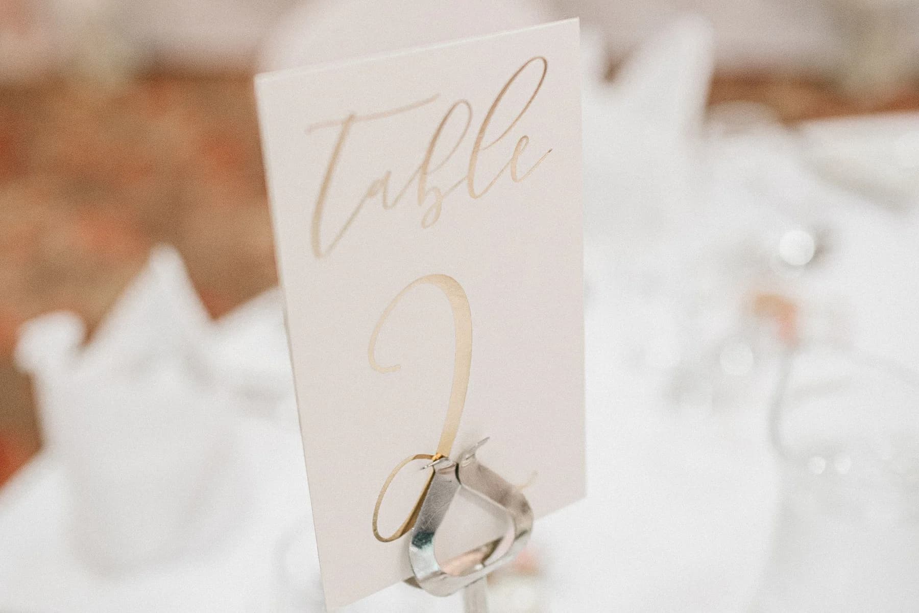 A pale table number 2 card held in a metal stand on a set wedding reception table